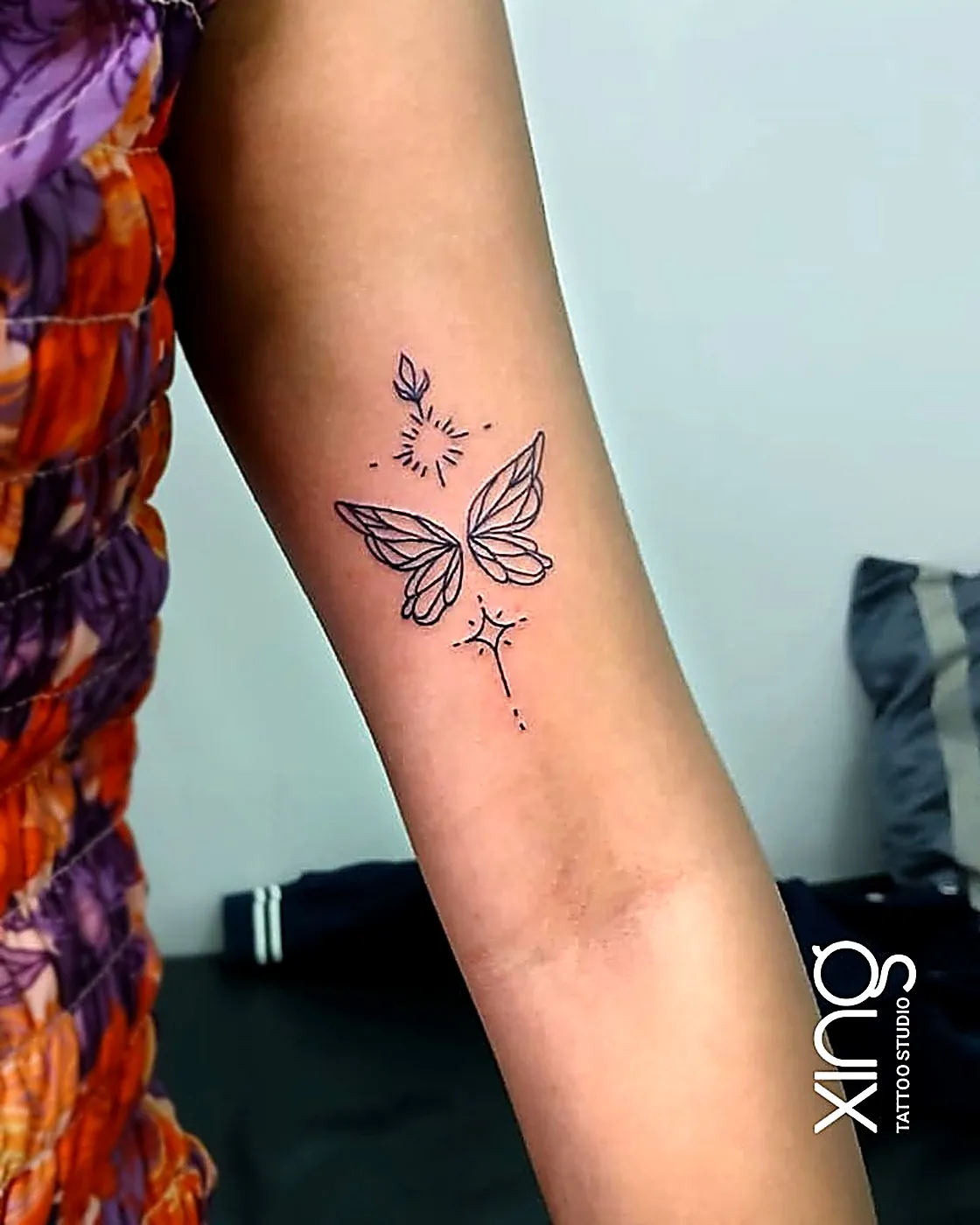 Fine-line sparkling butterfly tattoo on arm