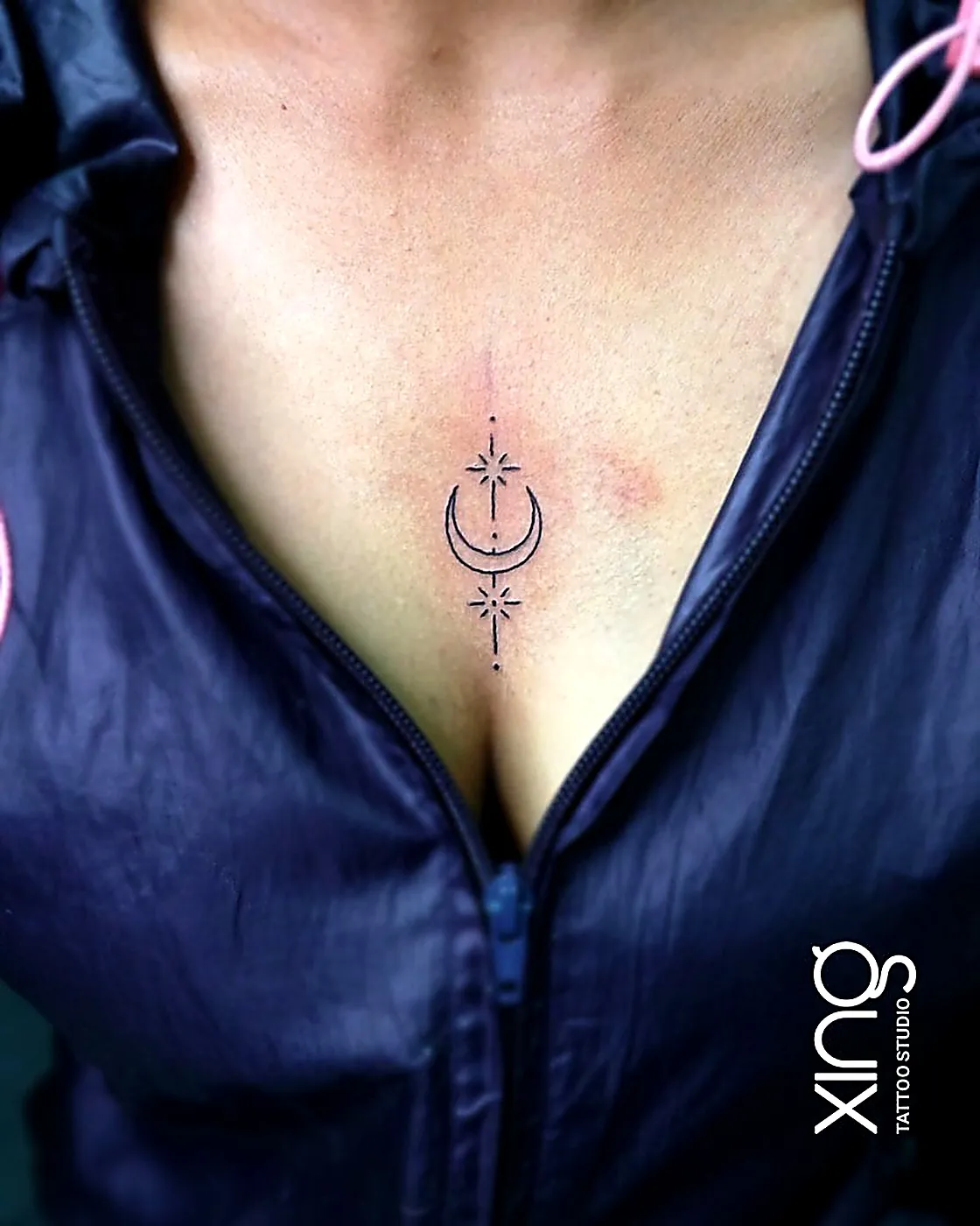 Fine-line moon and star tattoo on chest