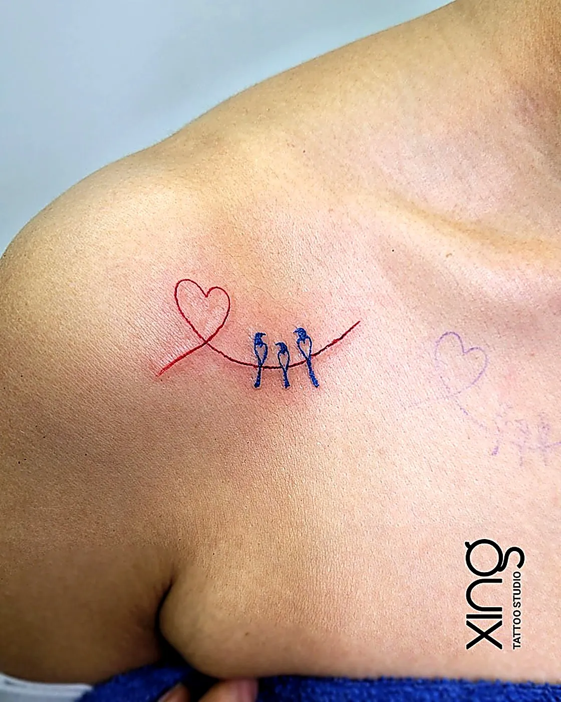 Fine-line heart and birds tattoo on collarbone