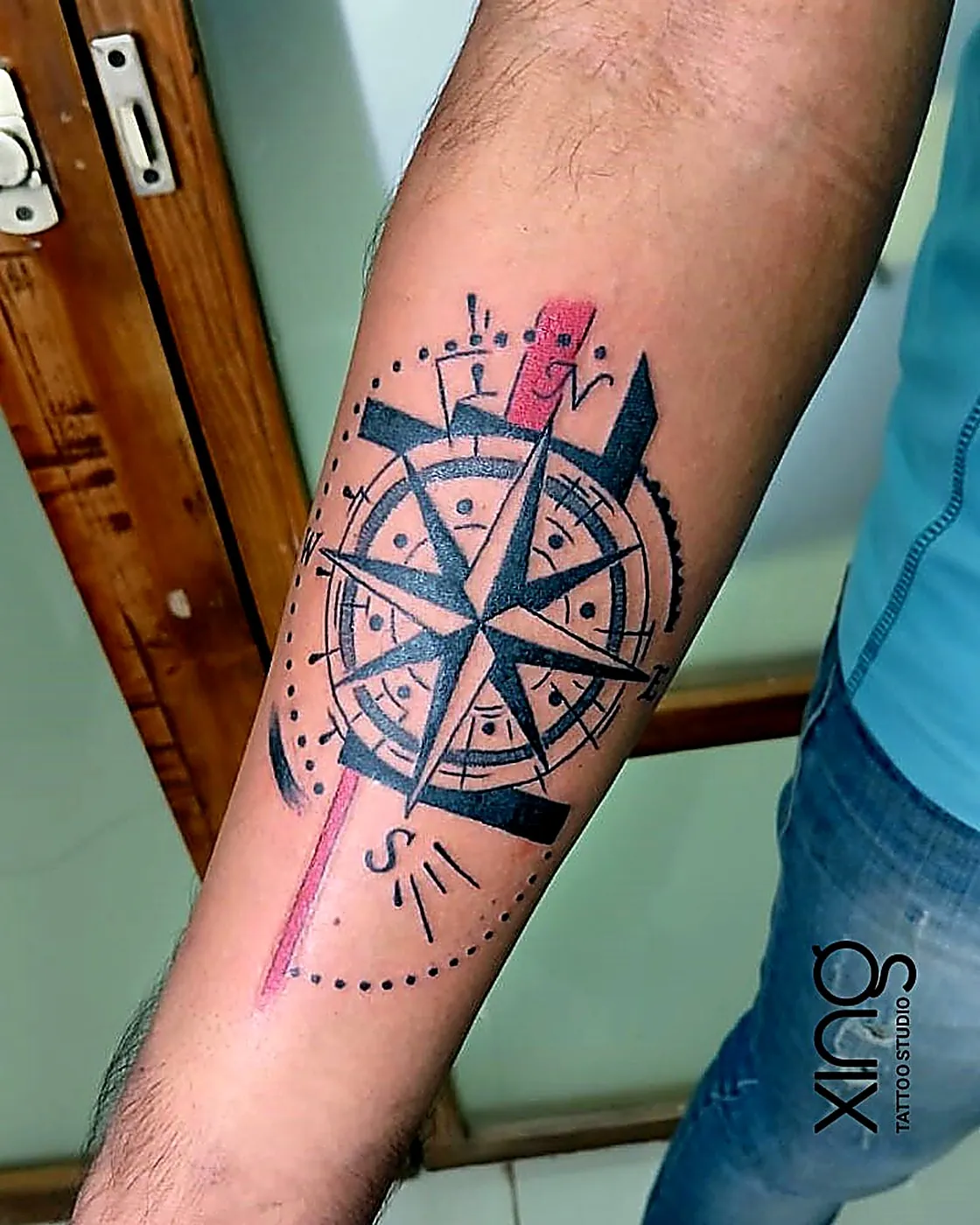 Colourful geometric compass tattoo on forearm