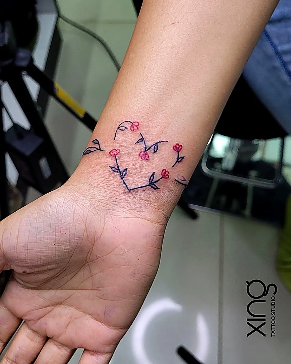Fine-line heart of flowers tattoo on wrist